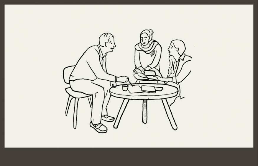 Three people sitting around a table discussing