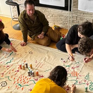 Team members painting a canvas on the floor