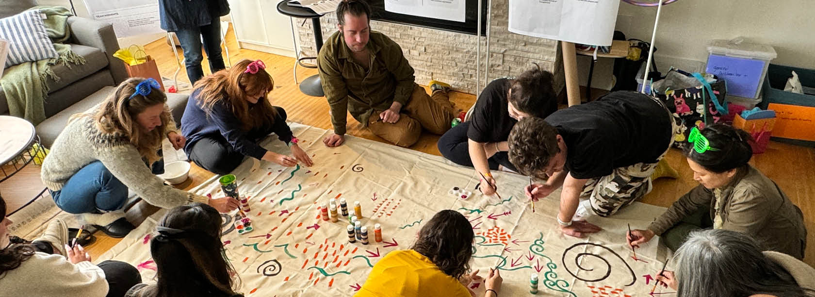 Team members painting a canvas on the floor